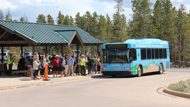 Visitors are in line and boarding the park's shuttle bus